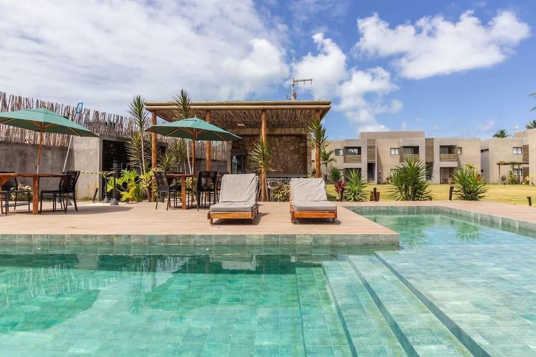 Piscina do condomínio com espreguiçadeiras e área de convivência