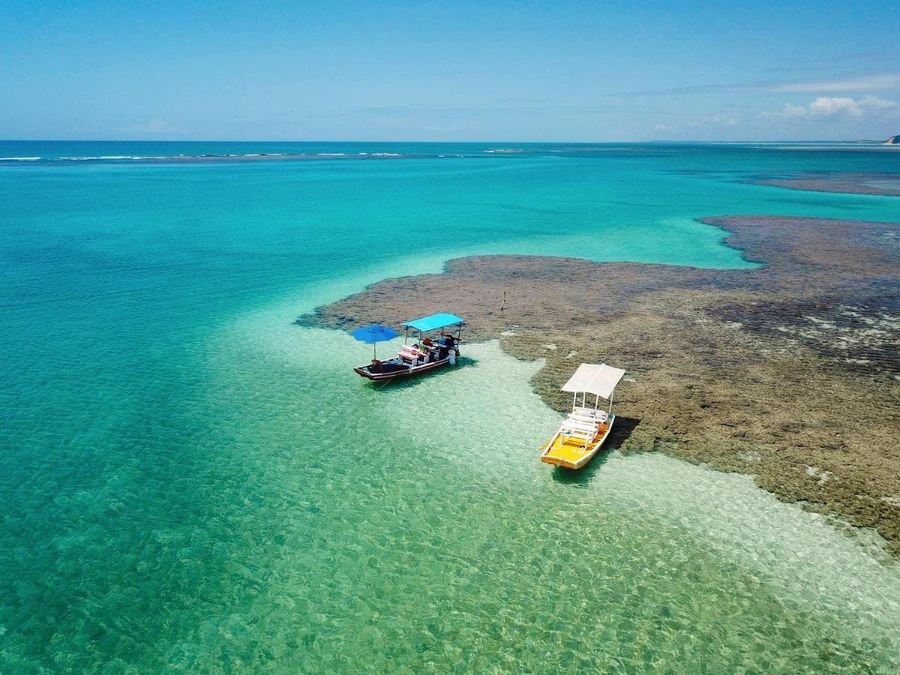 Piscinas naturais da Praia do Marceneiro, com barcos ancorados sobre recifes