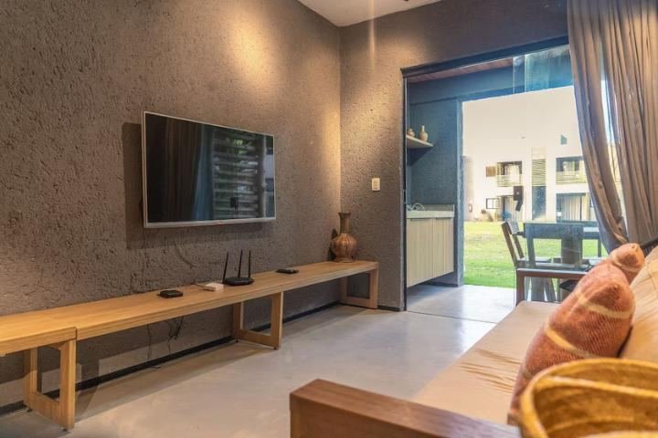 Sala integrada com bancada de madeira e decoração tropical