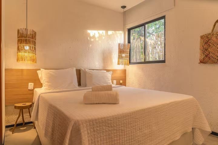Suíte com cama de casal e janela para a vegetação