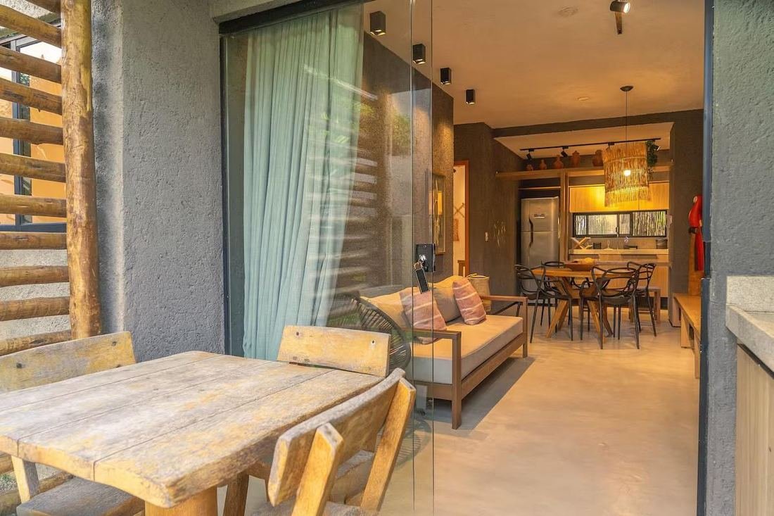 Varanda com mesa de madeira e vista para a sala
